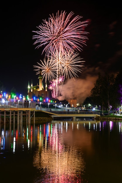 Kijk naar geweldig vuurwerk dat in de nachtelijke hemel gloeit