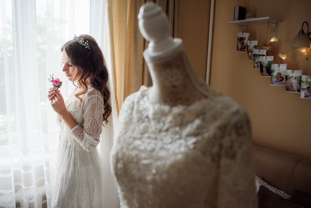 Kijk van achter de trouwjurk naar mooie bruid met een roze corsage