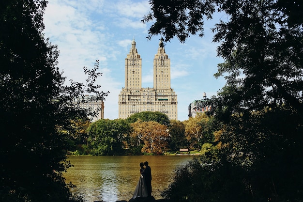 Kijk van veraf bij het bruidspaar zoenen voor het meer in Central Park in New York