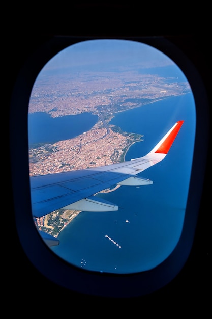 Kijken door raamvliegtuigen tijdens de vlucht in vleugelland boven Istanbul bij zonnig weer