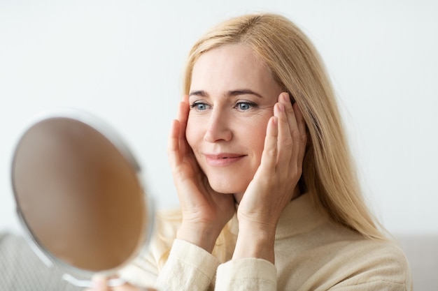 Kijkend naar een spiegelvrouw die haar gezicht aanraakt