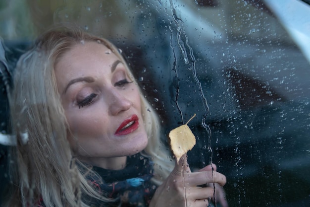 Foto kijkt door het regenachtige glas dat het meisje uit het autoraam op de regen valt met een perfect