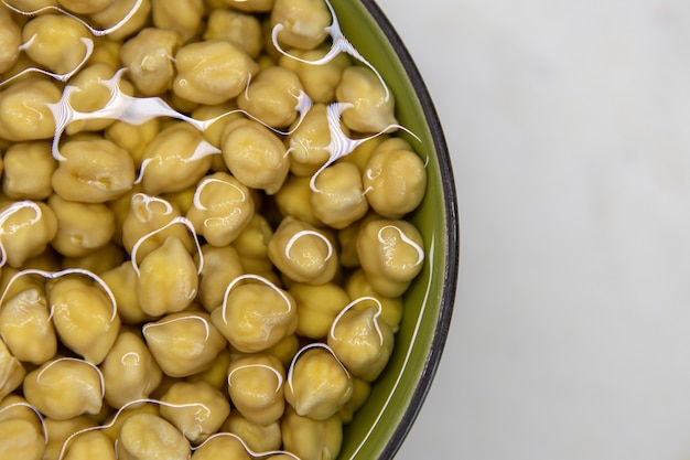 Foto kikkererwten gedrenkt in water, in kom, op marmeren tafel. concept van gezond eten, veganisme, vegetarisme, vlees- en eiervervanging. bereid kikkererwten voor voordat u hummus en andere peulvruchtengerechten maakt.