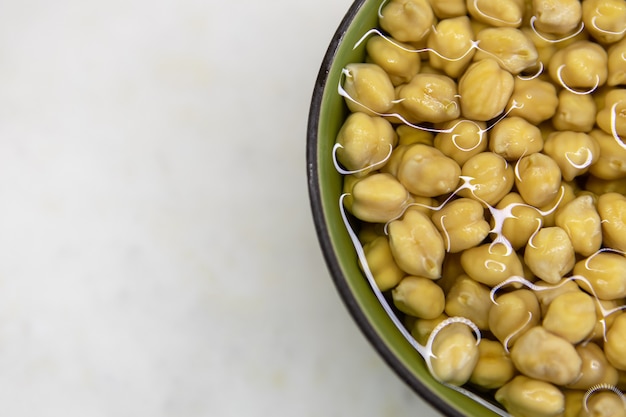 Kikkererwten gedrenkt in water, in kom, op marmeren tafel. Concept van gezond eten, veganisme, vegetarisme, vlees- en eiervervanging. Bereid kikkererwten voor voordat u hummus en andere peulvruchtengerechten maakt.