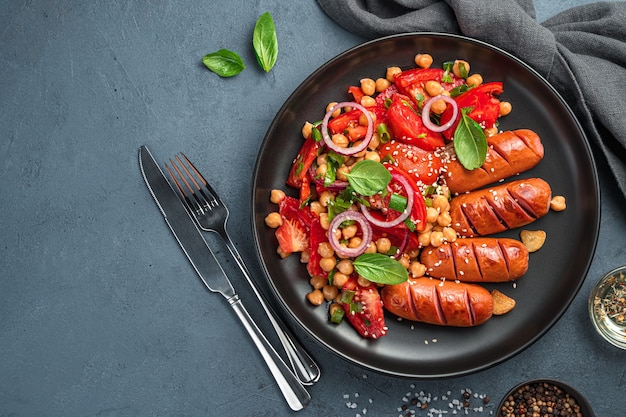 Kikkererwtensalade en gebakken worstjes op een donkere achtergrond