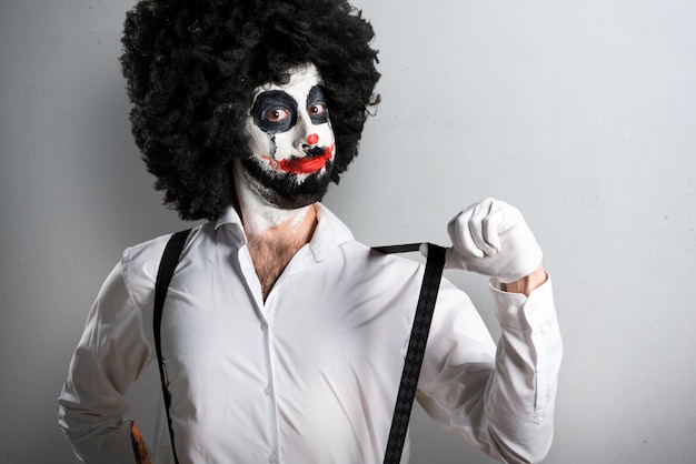 Killer clown with knife proud of himself on textured background