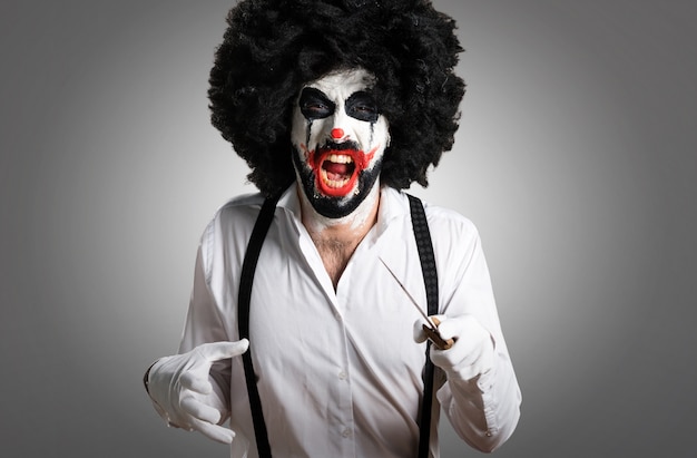 Killer clown with knife on textured background