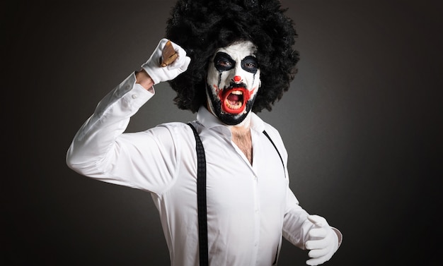 Killer clown with knife on textured background