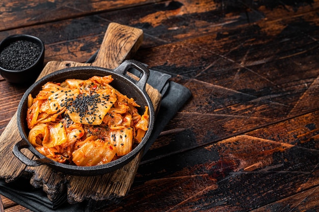Kimchi salted and fermented chinese cabbage in a skillet Wooden background Top view Copy space