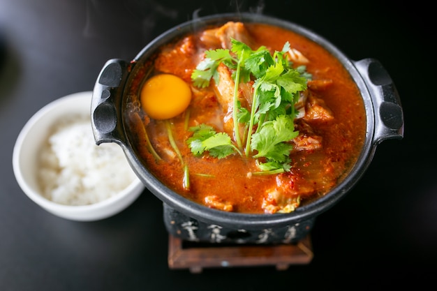 Photo kimchi soup with raw chicken eggs and white tofu, popular korean food.