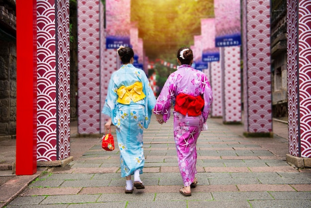 着物の日本の若い女の子は、晴れた日の夏休みに伝統的な衣装を着て、日本の地元の歴史文化の小道を歩き、日本の地元のお祭りに参加します。