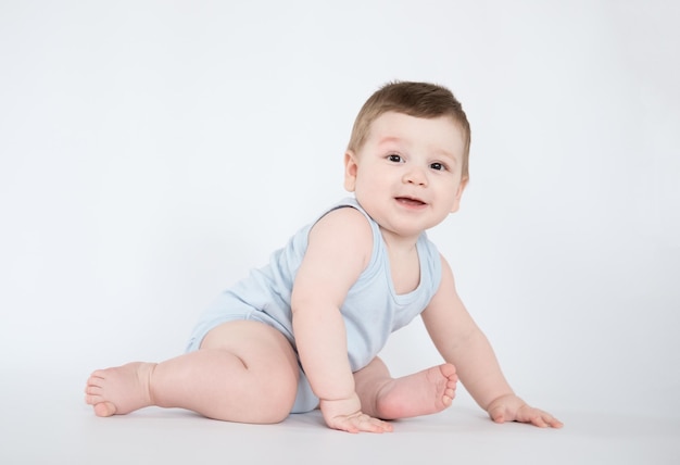 Kind babyjongen zit gelukkig lachende jongen op een witte achtergrond van 7 maanden