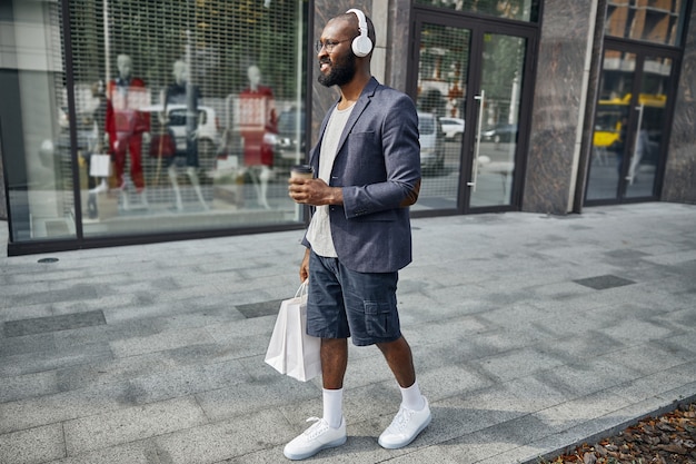 Kind bearded man expressing positivity while listening to music during walk