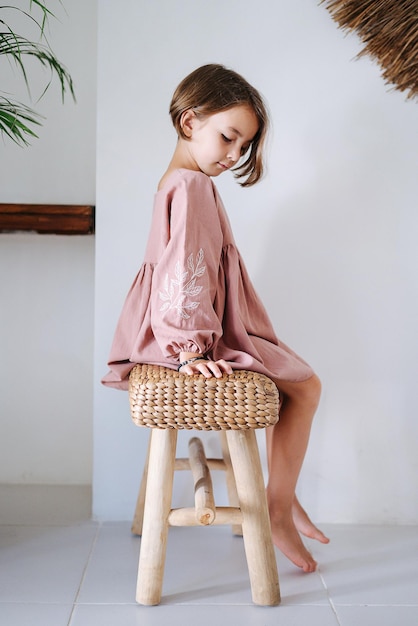 Kind bescheiden zittend op een houten stoel zijkant