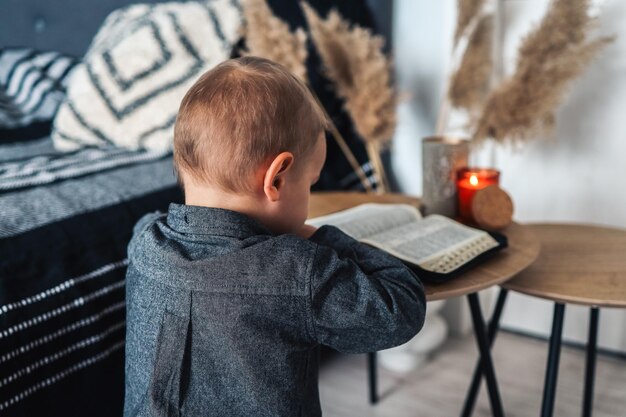 Kind bidt en leest de Bijbel in het religieuze concept van zijn kamer