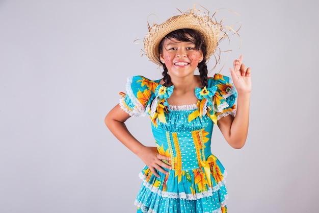 Kind Braziliaans meisje met Festa Junina kleding vingers gekruist geluksteken juichen