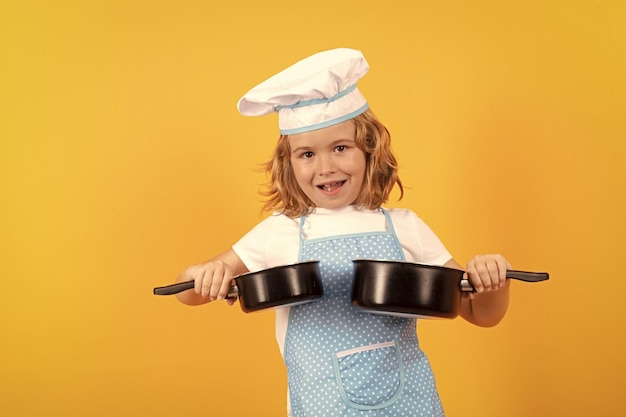 Kind chef-kok met kookpot stockpot Kind in kok uniform en chef hoed het bereiden van eten op studio kleur achtergrond Koken culinaire en kinderen voedsel concept