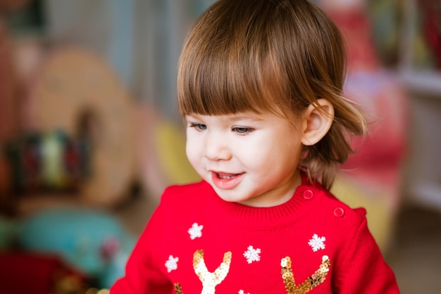 Kind close-up portret van meisje in rode trui te wachten om cadeautjes te ontvangen voor Kerstmis en n...