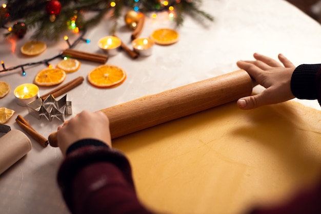 Kind dat het deeg voor koekjes met gedecoreerde Kerstmisachtergrond vormt