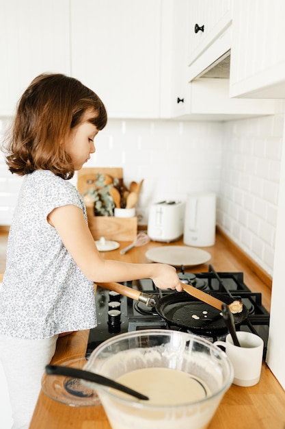 Kind dat pannenkoeken maakt voor het ontbijt Echte mensen thuisleven