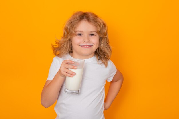 Kind drinkt melk met grappige emoties op gele achtergrond Kind drinkt melk studioportret Schattig kind met melksnor houdt een glas melk