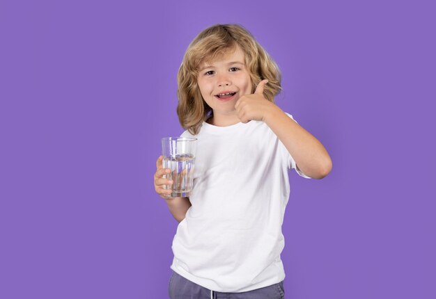 Kind drinkt zoet water geïsoleerd op studio achtergrond kind houdt glas helder water gezond leven