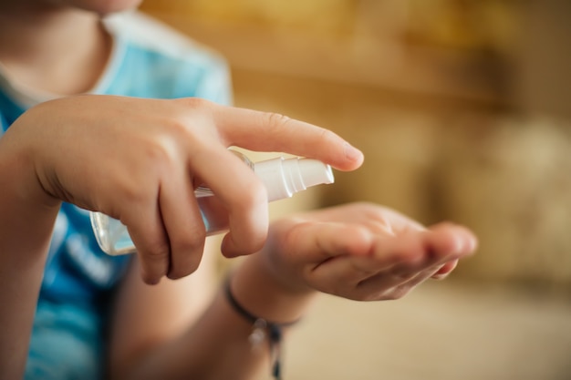 Kind drukt dispenseruitloop voor antibacteriële vloeistof om de huid tegen virussen te behandelen. Bescherming tegen coronavirus. Voorkomen van infectie behandeling van huid van handen met desinfectiemiddel.