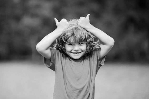 Kind duimen omhoog. Kind jongen keurt goed. Portret van lachende kleine jongen duimen opdagen.