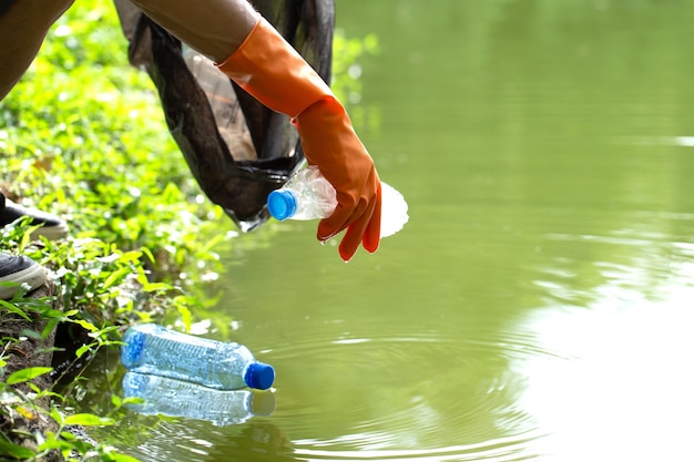 Kind ecofriendly volunteers holding packets and gathering plastic bottle garbage from water