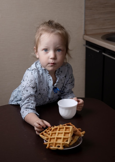 Kind eet wafels aan tafel