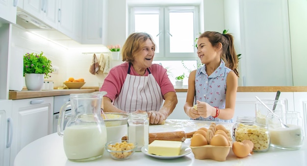 Kind en grootmoeder in de keuken bakt het deeg in de keuken Selectieve focus Voedsel