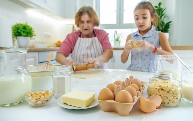 Kind en grootmoeder in de keuken bakt het deeg in de keuken Selectieve focus Voedsel