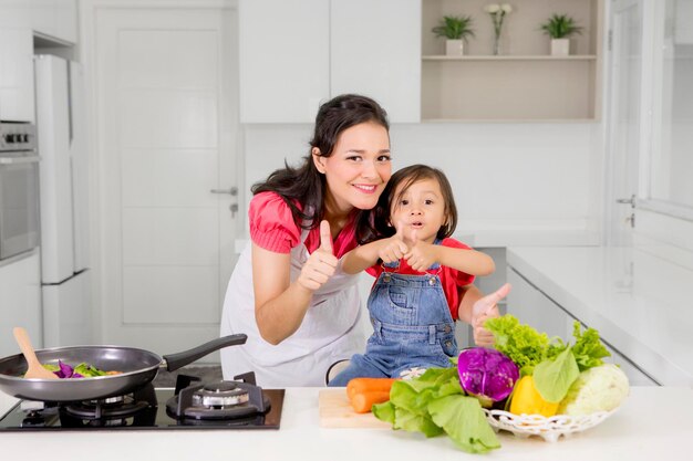 Kind en moeder die OK teken in keuken tonen