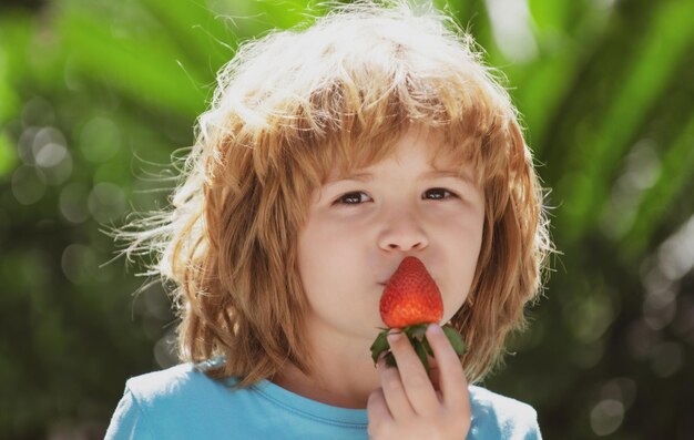 Kind eten aardbei op groene zomer achtergrond