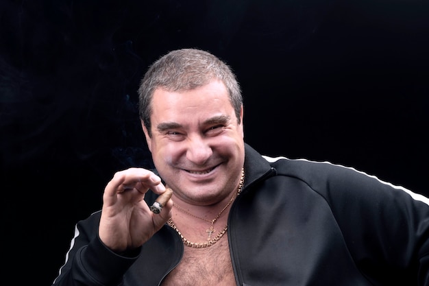 A kind, genuinely laughing white fat man, smoking a cigar. sincere emotions. A good-natured adult man, a portrait on a black background