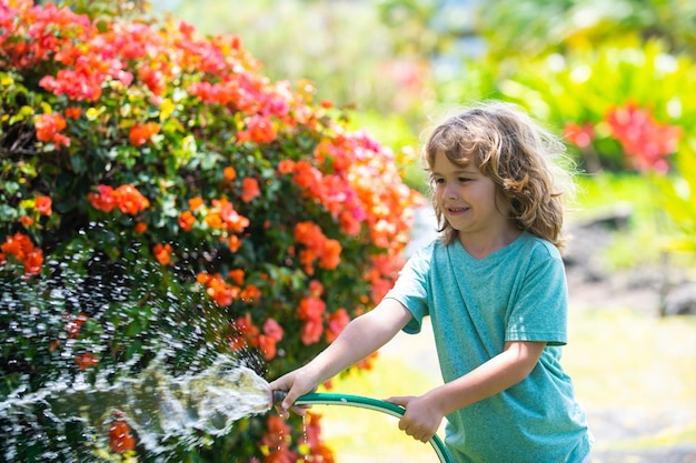 Kind heeft plezier in de binnenlandse tuin Kind houdt de tuinslang water geven actieve buitenspellen voor kinderen in