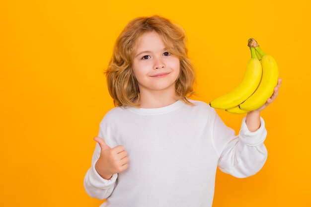 Kind houd banaan in studio Studio portret van schattige jongen jongen met bananen geïsoleerd op geel