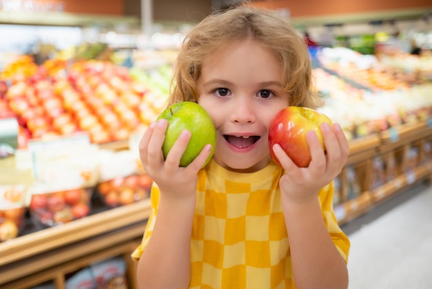 Kind houdt appelfruit in de supermarkt kind bij het winkelen in de supermarkt kruidenierswinkel die goederen kiest