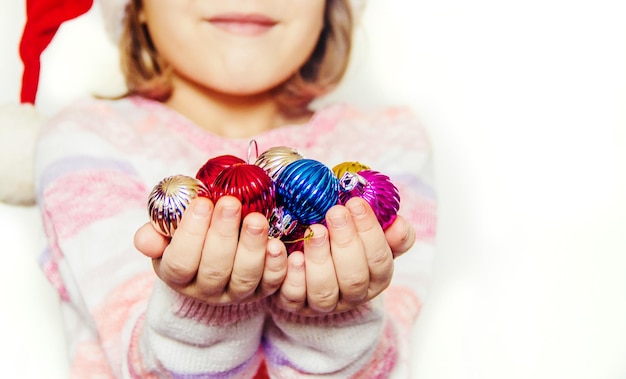 Kind houdt een kerstdecor en geschenken op een witte achtergrond Selectieve aandacht