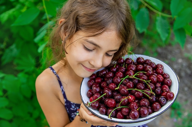 Kind houdt een kom met kersen op tuinachtergrond