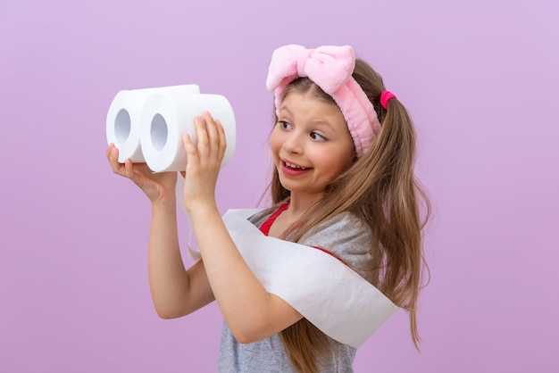 Kind houdt twee rollen toiletpapier vast op lichtpaarse achtergrond