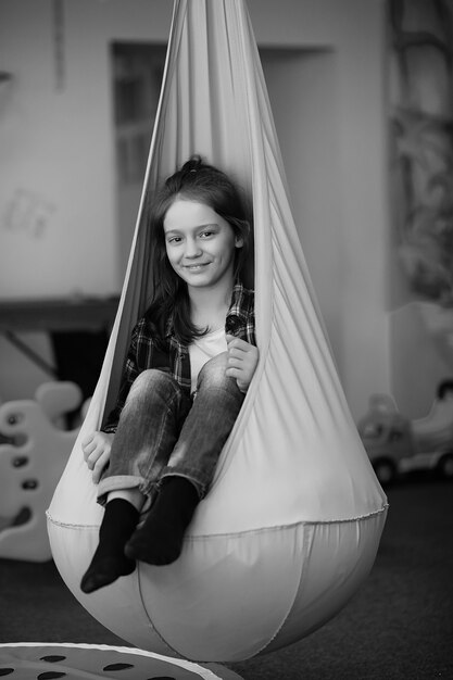 Kind in de kinderkamer. Het kind zit op de vensterbank bij het raam. Gelukkig kind met speelgoed.