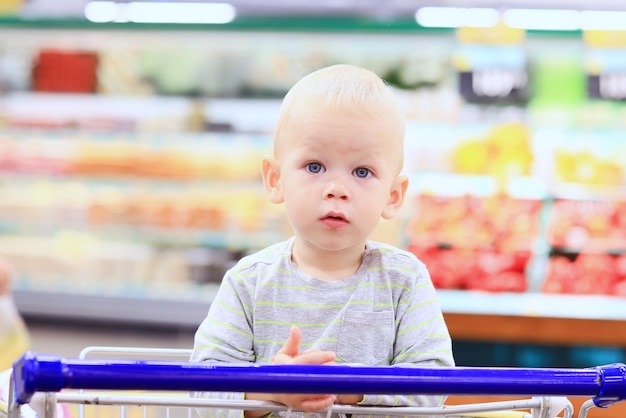 kind in de winkel op het boodschappenkarretje is een kleine klant