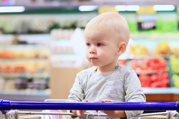 kind in de winkel op het boodschappenkarretje is een kleine klant