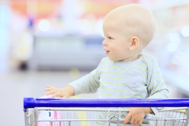 kind in de winkel op het boodschappenkarretje is een kleine klant