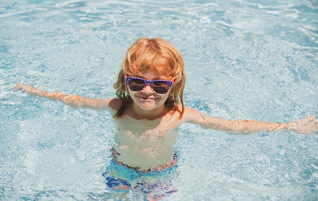 Kind in de zomer zwembad schattige jongen in het water spelen met water lachende schattige kleine jongen in su