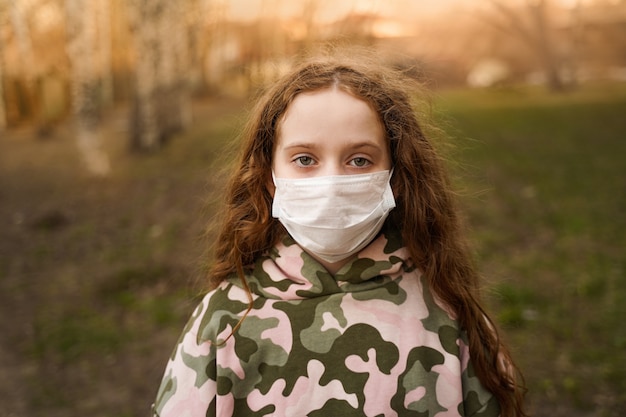 Foto kind in een medisch masker buitenshuis.