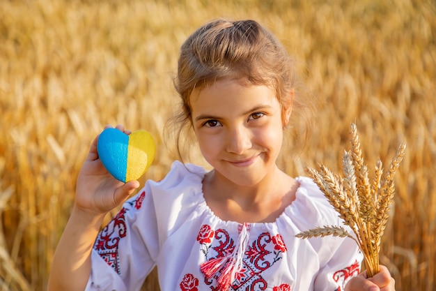 Foto kind in een tarweveld. in vyshyvanka, het concept van de onafhankelijkheidsdag van oekraïne. selectieve aandacht.