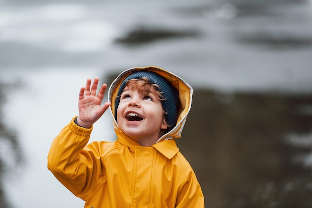 Kind in gele waterdichte mantel en laarzen die buiten spelen na de regen