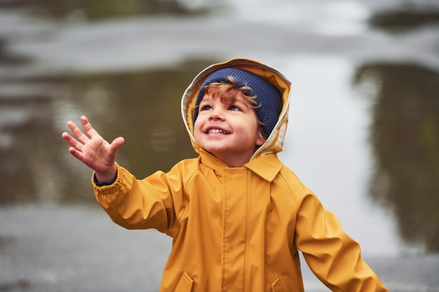 Kind in gele waterdichte mantel en laarzen die buiten spelen na de regen